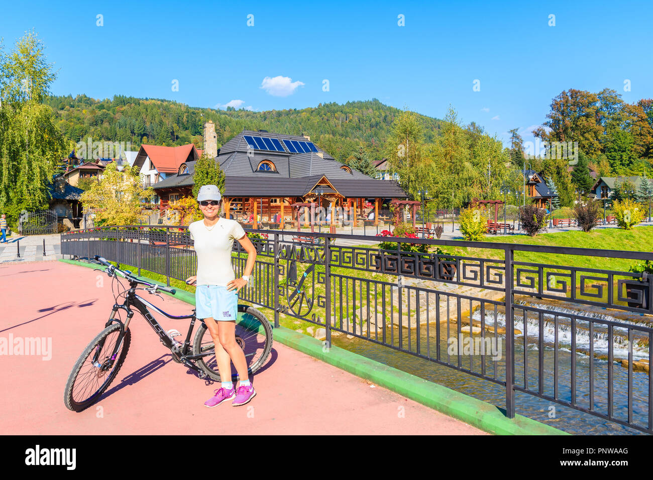 SZCZAWNICA, POLAND - SEP 19, 2018: Young woman bicyclist standing on bridge in Szczawnica. This place is a well-known resort town famous for its favor Stock Photo