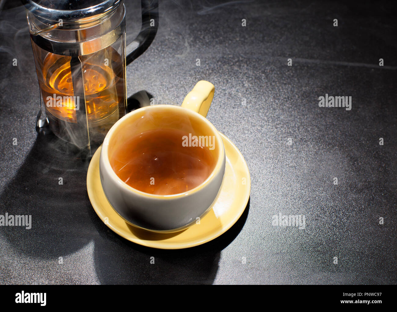 Smoky hot tea in a cup with a tea press maker Stock Photo