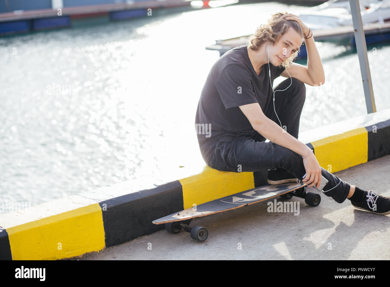 hipster man sitting on longboard using his phone Stock Photo