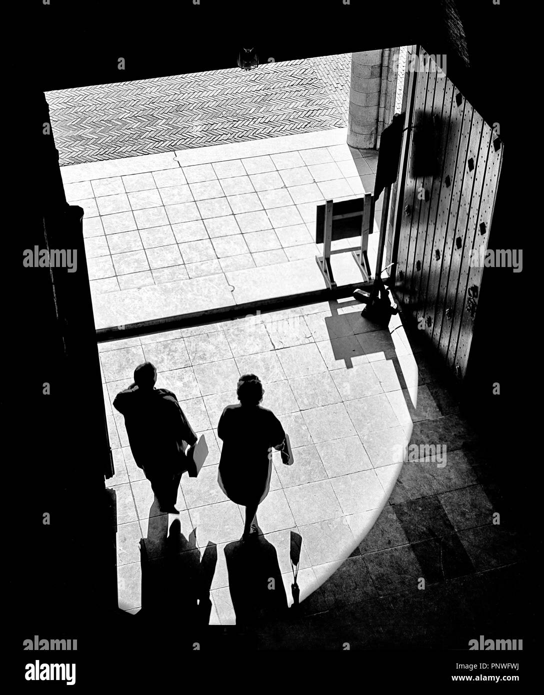 Two people stepping out of a dark building into sun shines Stock Photo