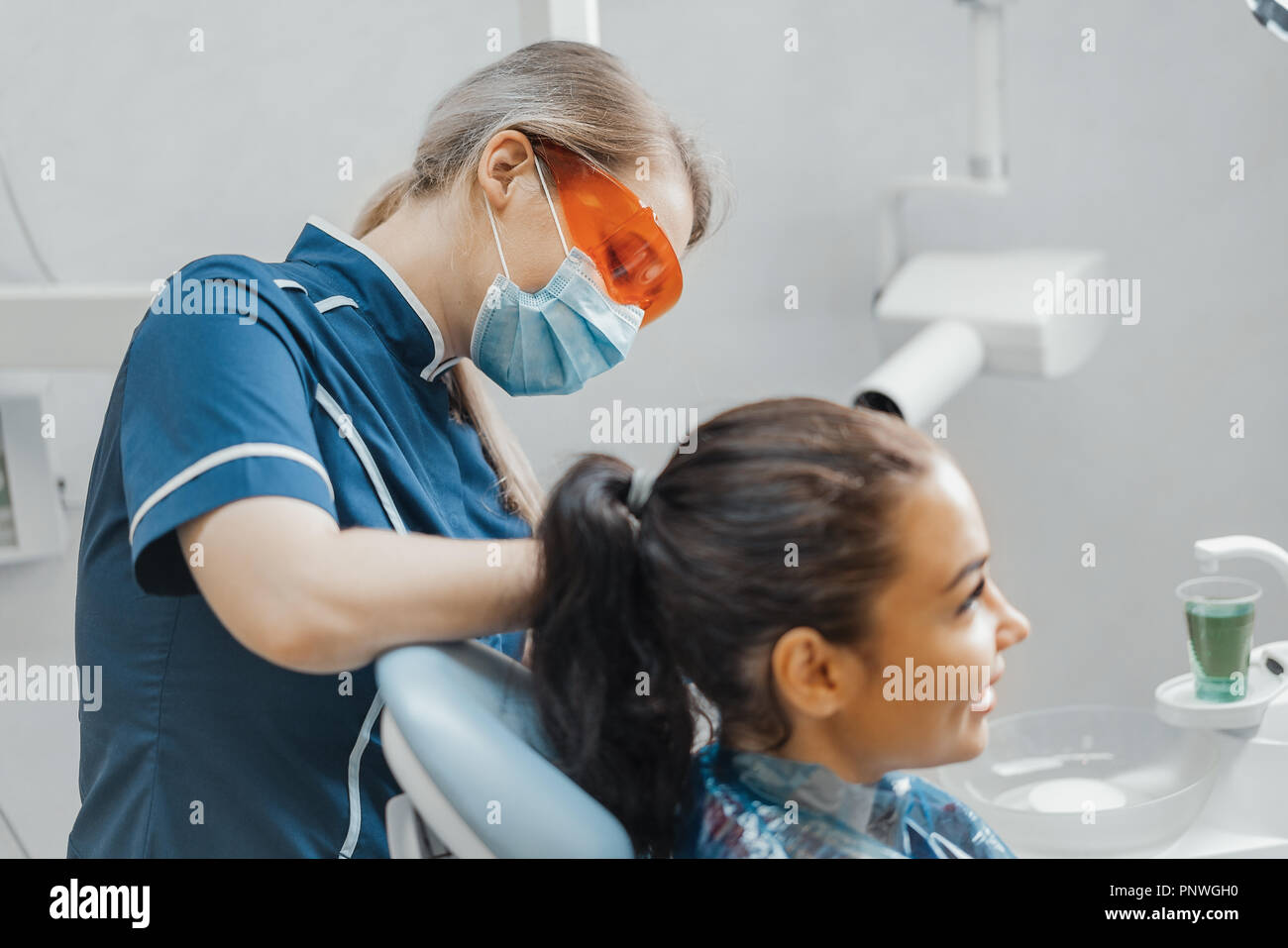 Close up of woman dentist putting on plastic apron on smiling woman