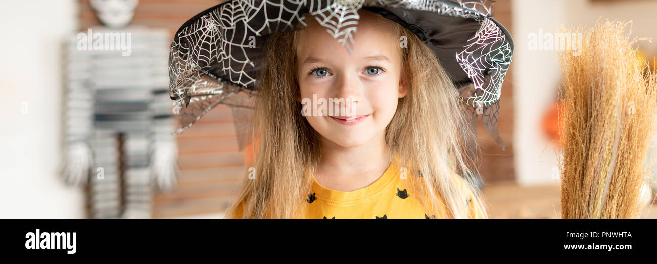 Cute Little Girl In Witch Costume Holding A Broom Is
