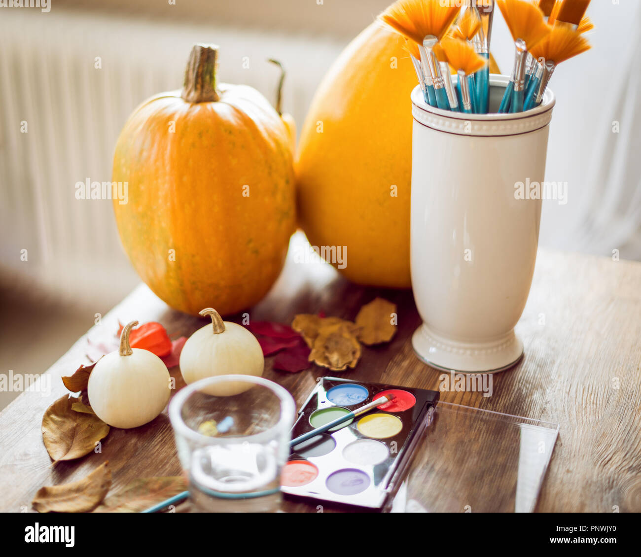 DIY Halloween concept. Art and craft, decorating Halloween pumpkins. Color pallete, paintbrush and pumpkins on wooden table. Stock Photo
