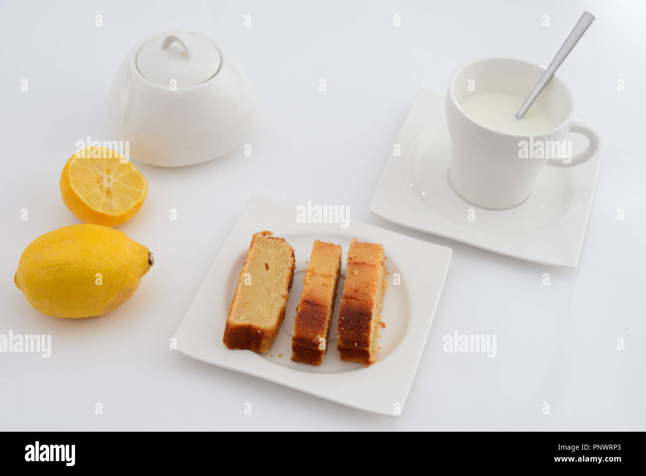 Breakfast. Cup with milk and lemon sponge cake on a plate. White background Stock Photo