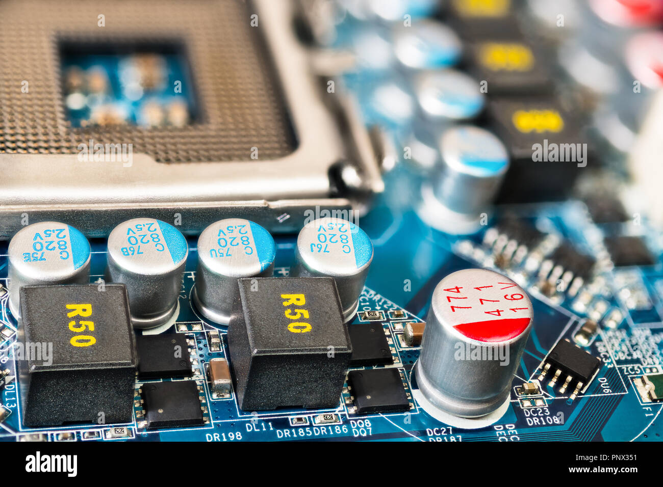 Computer mainboard detail. Pulse source circuits. Hardware electronic components close-up. CPU socket, inductors, capacitors. Surface mount technology. Stock Photo