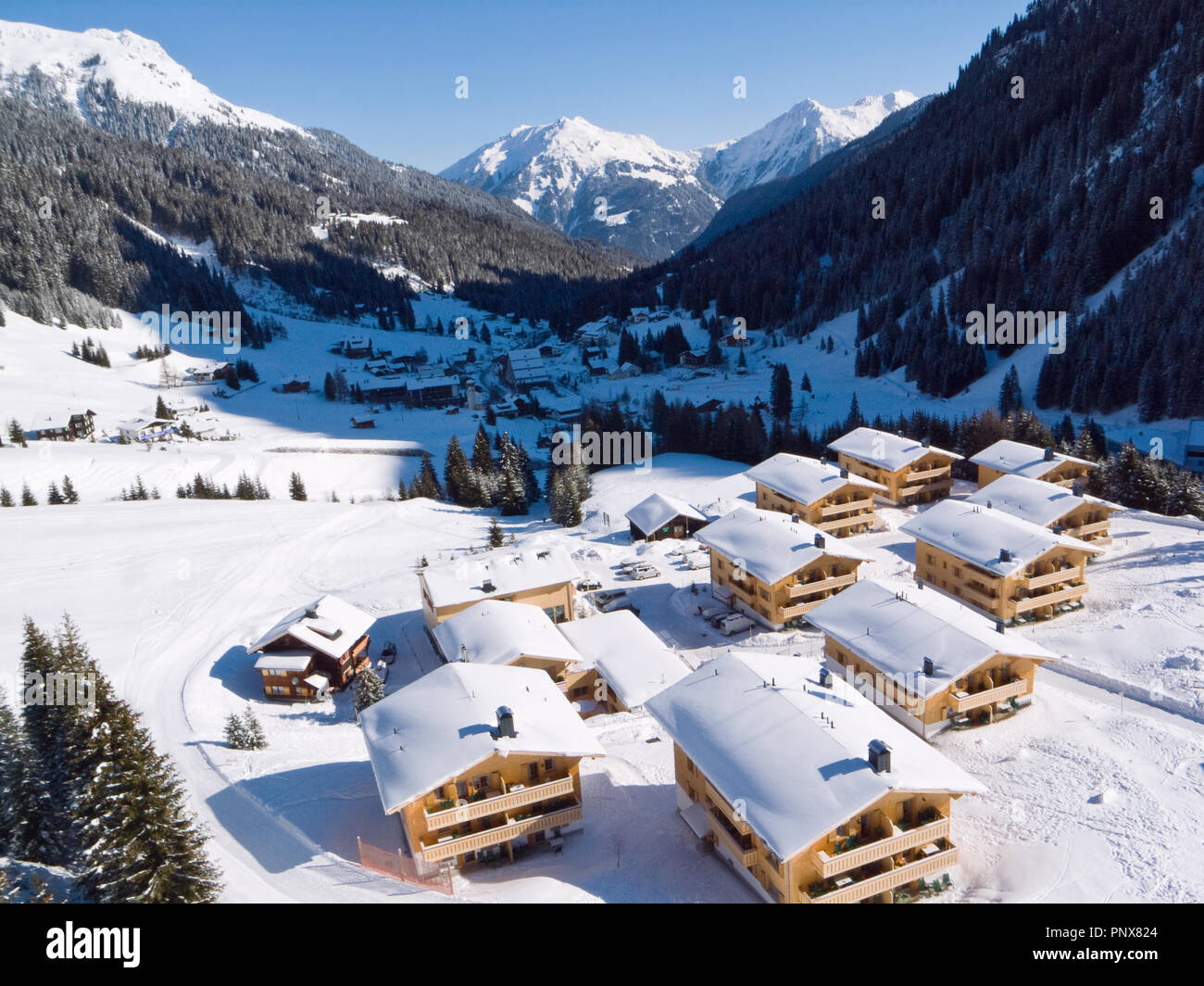 Gargellen, a village in the Austrian Alps, with snow covered chalets in the foreground and mountains in the background. Stock Photo