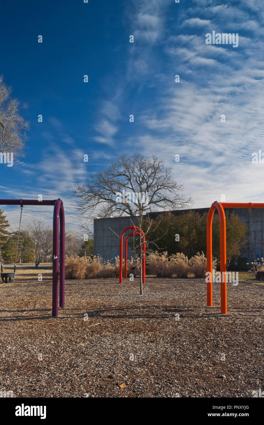 Three swing sets (one purple, one red, one orange) at St. Louis Forest Park on a sunny winter day with a few altocumulus clouds. Stock Photo