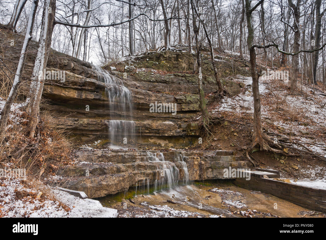 Snowmelt causes a waterfall to pour over the Dripping Springs cascade at (St. Louis) Creve Coeur Park as March comes in like a lion with snow. Stock Photo