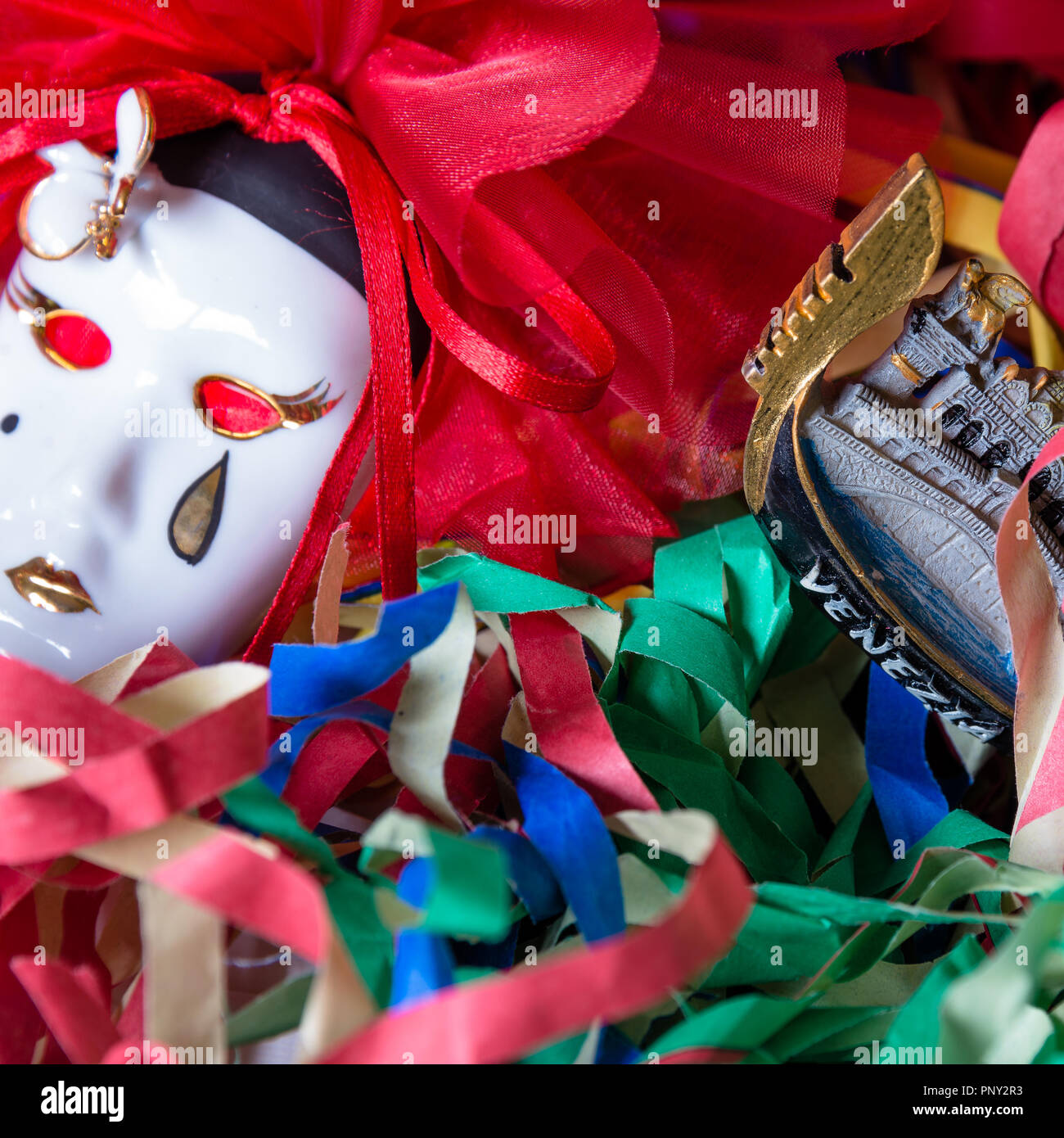 Close-up of Pierrot carnival mask on a background of colored streamers Stock Photo