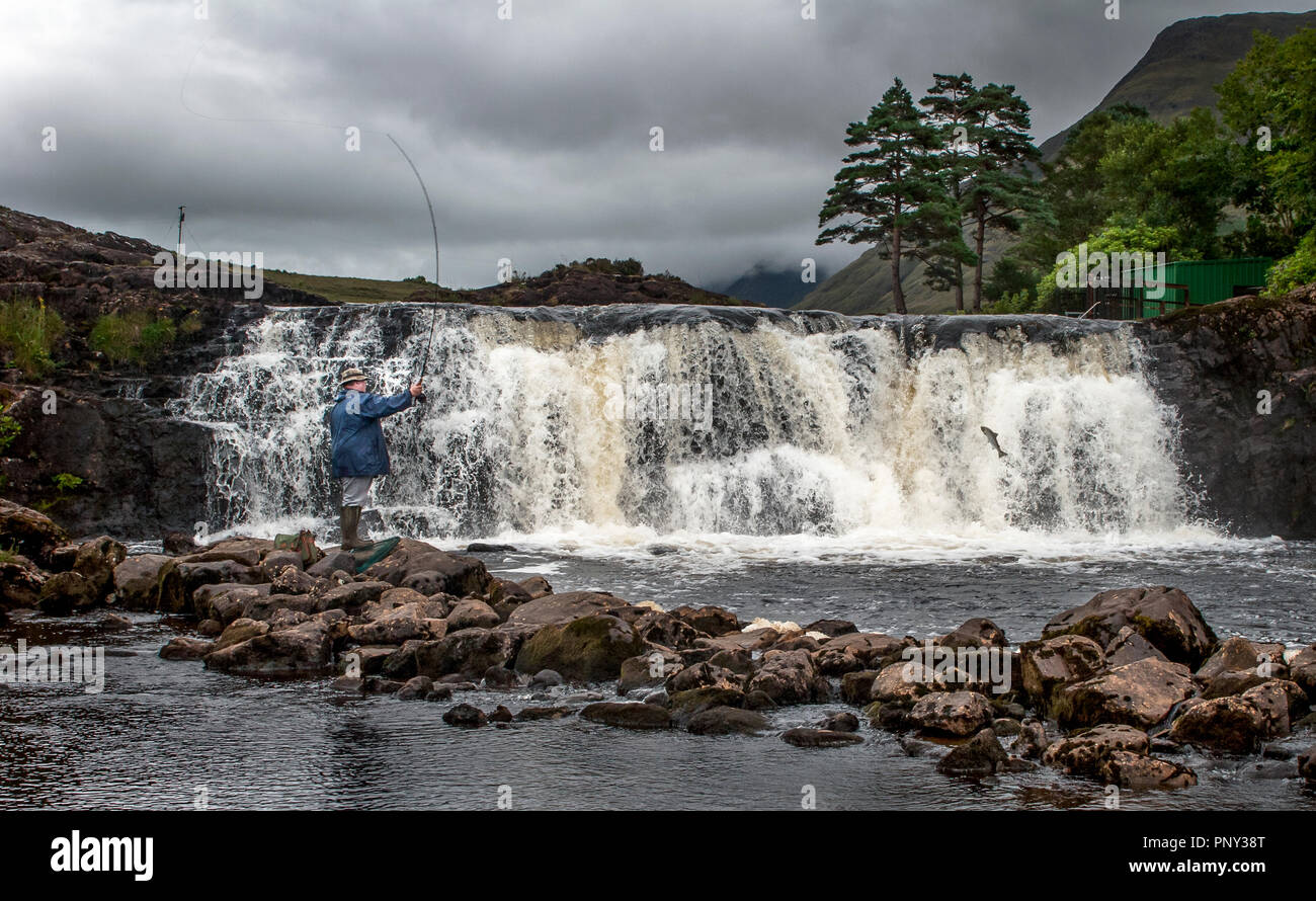 Ashleigh Falls, Mayo, Ireland. 06th August 2006. A angler on a fishing holiday casts his line while a Salmon attempts to  leap the falls on its way up Stock Photo