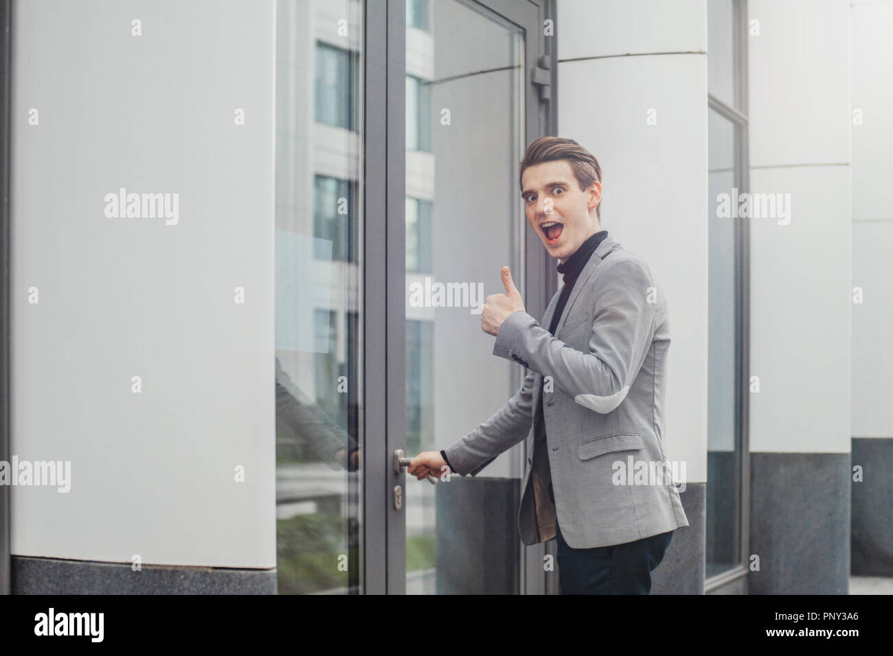 Close up of young business man opening door of modern business center. Stock Photo