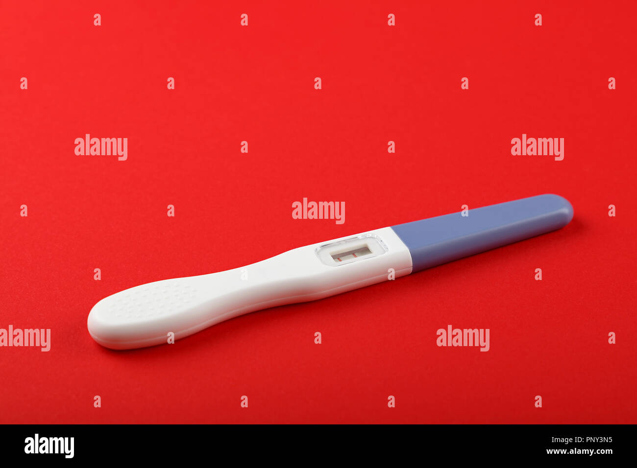Close up one positive (pregnant) result pregnancy test over red paper background, high angle view Stock Photo