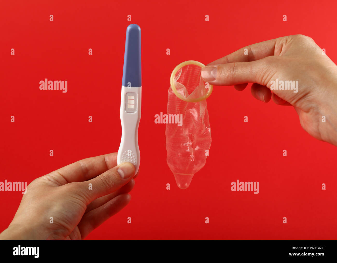 Close up woman hands holding positive (pregnant) pregnancy test and condom  over red background with copy space, low angle view, personal perspective  Stock Photo - Alamy