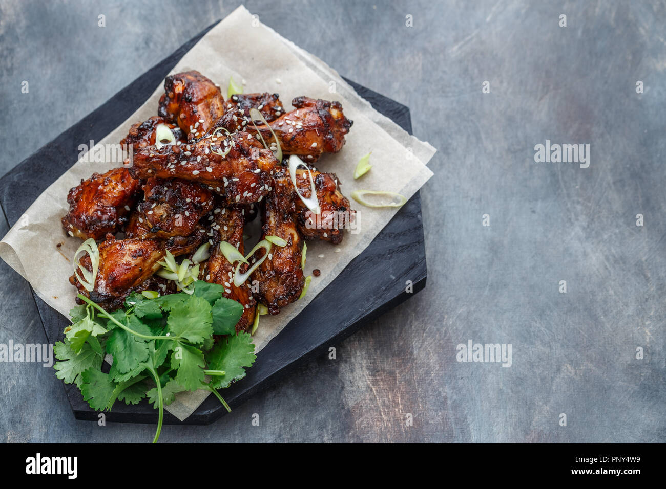 Baked chicken wings with sesame and sauce. Food background with copy space. Top view. Stock Photo