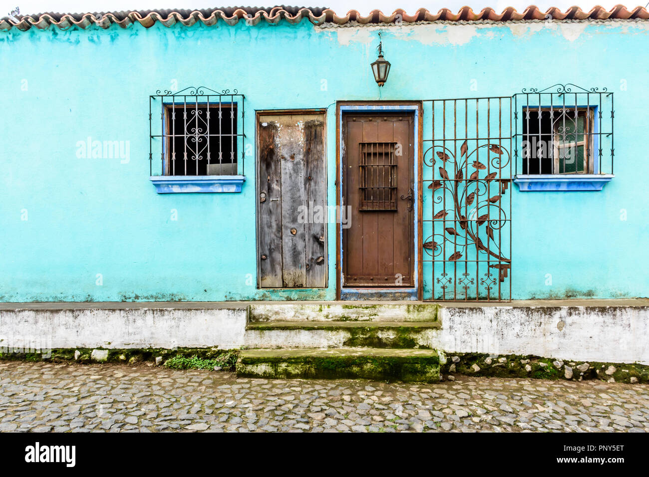 Turquoise painted house exterior with decorated wrought iron bars on  windows & door in cobbled street in Guatemala, Central America Stock Photo  - Alamy