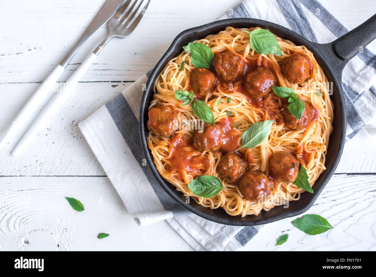 Spaghetti pasta with meatballs, tomato sauce and fresh basil in cast iron pan. Healthy homemade
