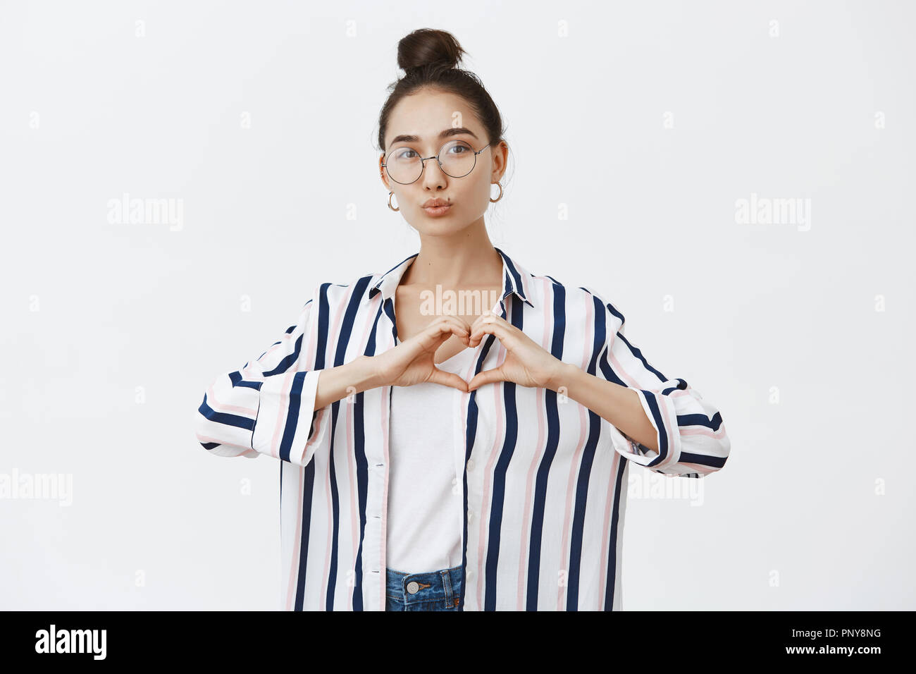 Good-looking feminine fashion blogger shaping heart with hands