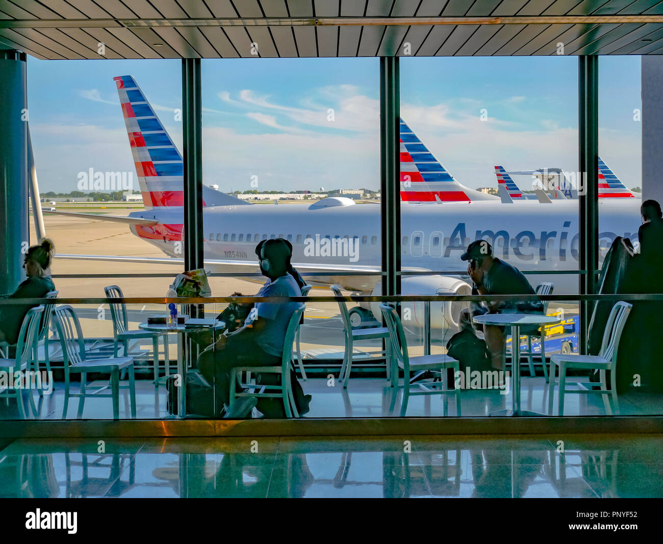 Travelers seated at tables with view of airliners out window. Terminal 3, O'Hare International Airport. Chicago, Illinois. Stock Photo
