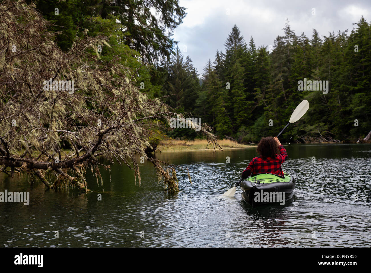 Girl kayaking in a river during a cloudy summer day. Taken in Cape