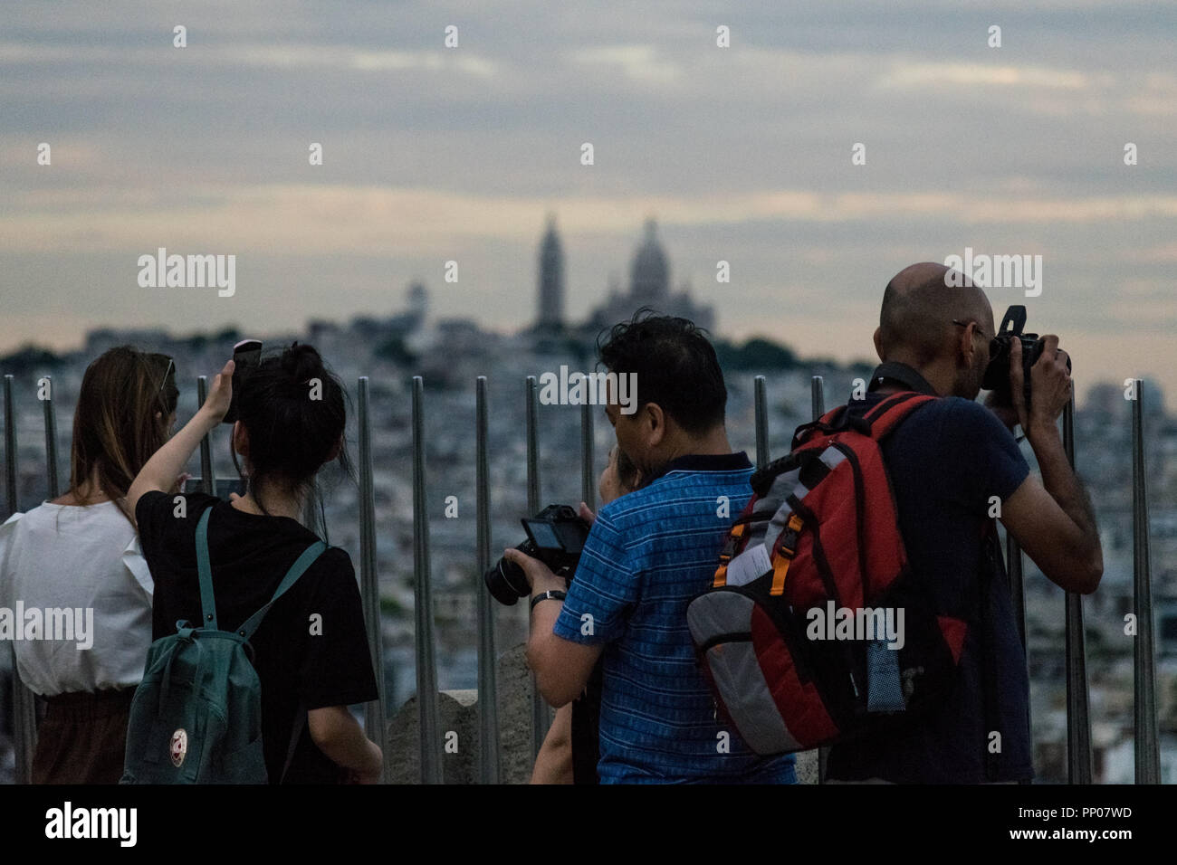 Tourists enjoying the view from Arc de Triomphe rooftop, with Basilique du Sacré-Cœur in the background Stock Photo