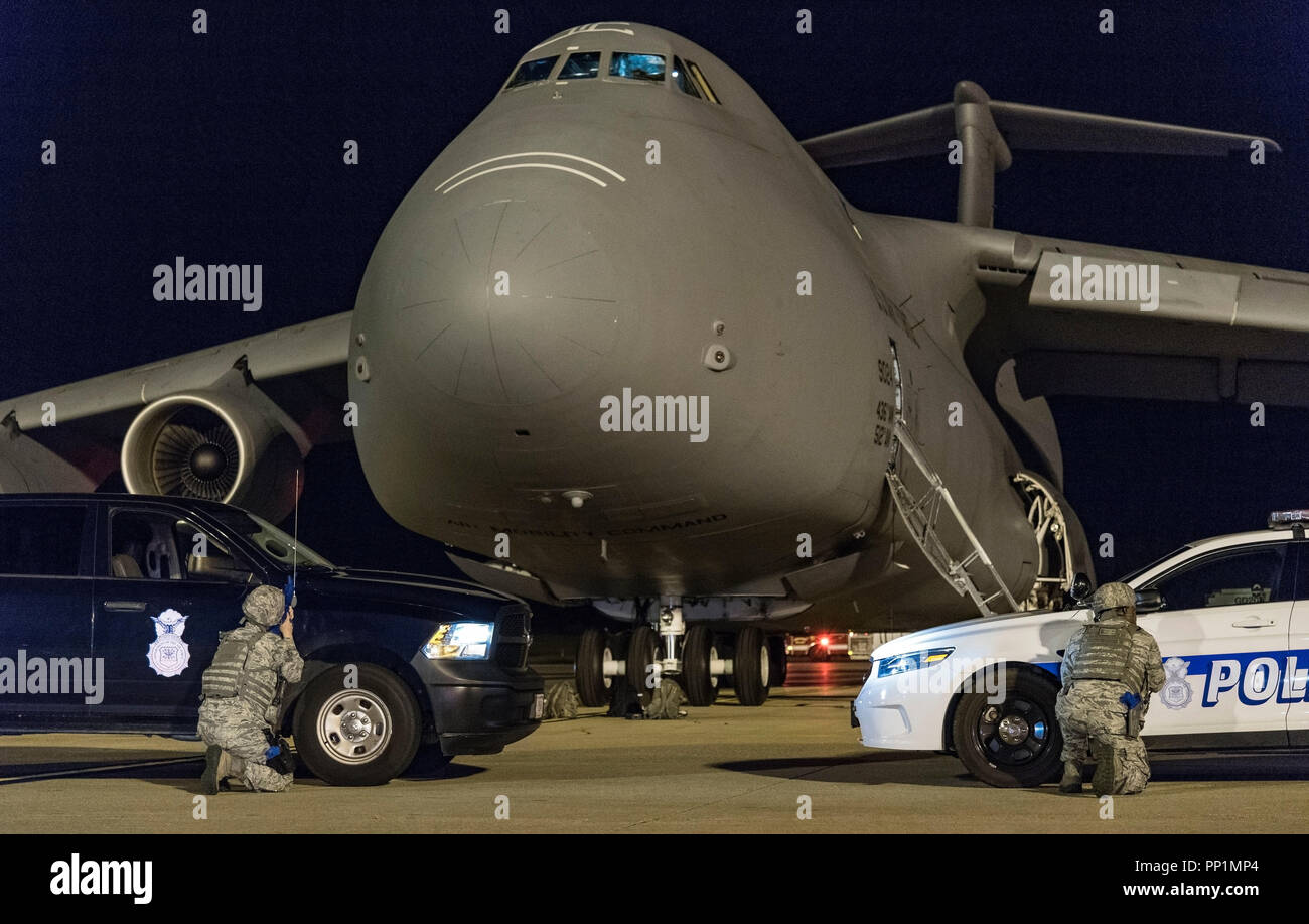 Two 436th Security Forces Squadron response force members take cover behind their vehicles positioned in front of a C-5M Super Galaxy as part of anti-hijacking measures Sept. 17, 2018, on Dover Air Force Base, Del. More than 20 response force members and other first responders positioned themselves and vehicles around the C-5M in response to a simulated attempted hijacking and hostage scenario. (U.S. Air Force photo by Roland Balik) Stock Photo