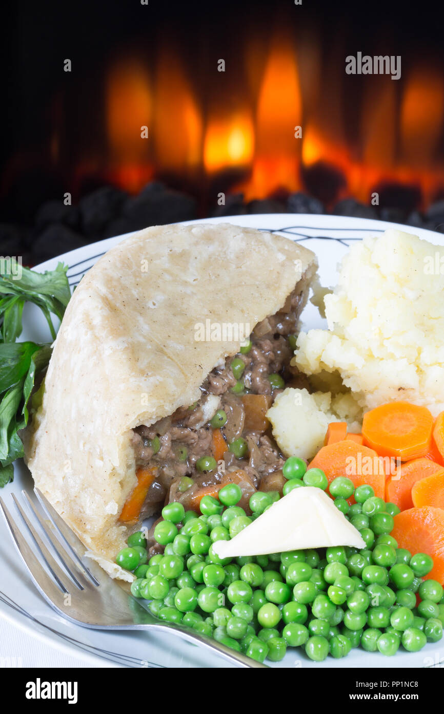 English pub/restaurant dish of steamed beef pudding served with garden Peas, sliced Carrot and mashed Potato, Stock Photo