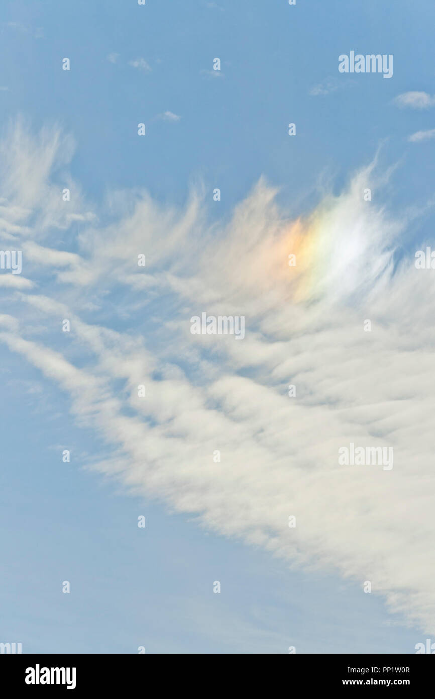 Feather-like cirrus clouds refracting sunlight to create a sundog against an indigo backdrop at the end of December. Stock Photo
