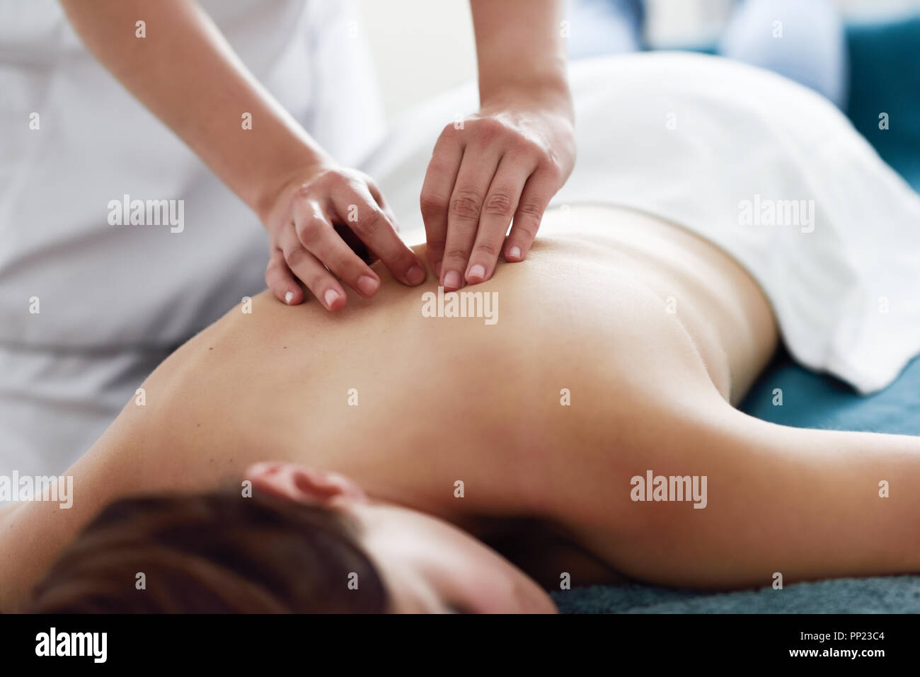 Young woman receiving a back massage by professional therapist. Female patient is receiving treatment in a spa center. Stock Photo