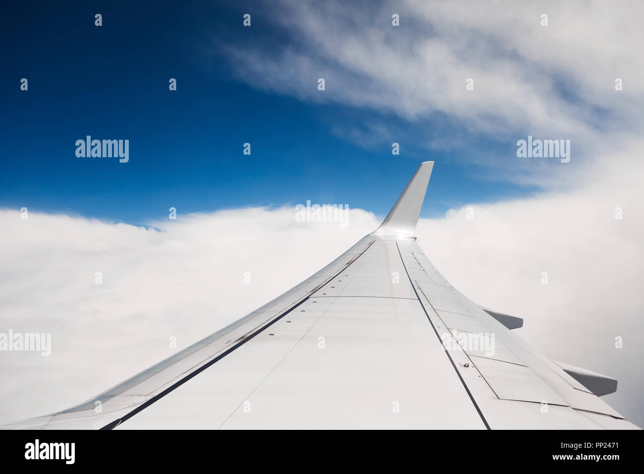 Wing of an airplane flying above the clouds. Stock Photo