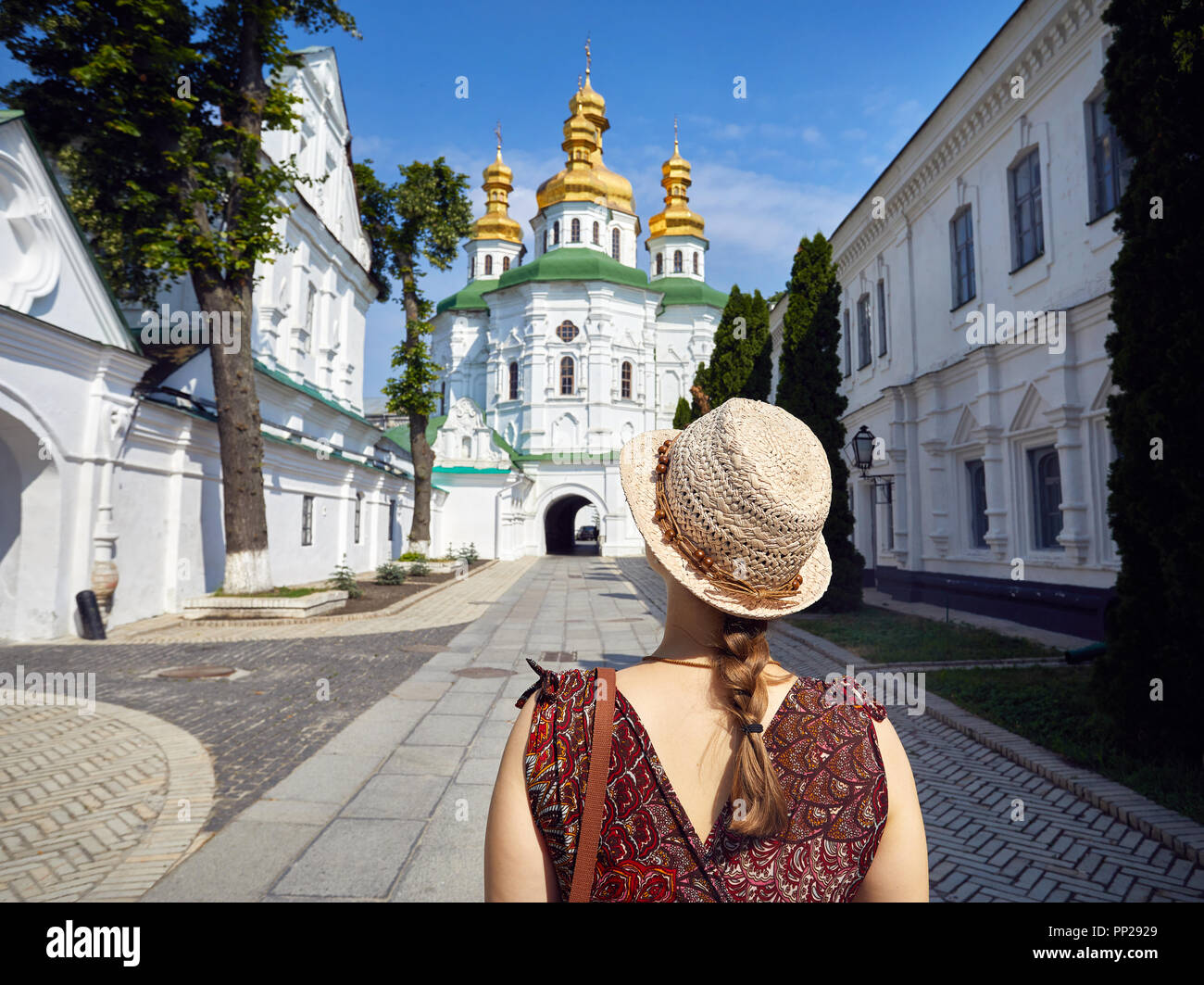 Woman in hat looking at Church with golden domes at Kiev Pechersk Lavra Christian complex. Old historical architecture in Kiev, Ukraine Stock Photo