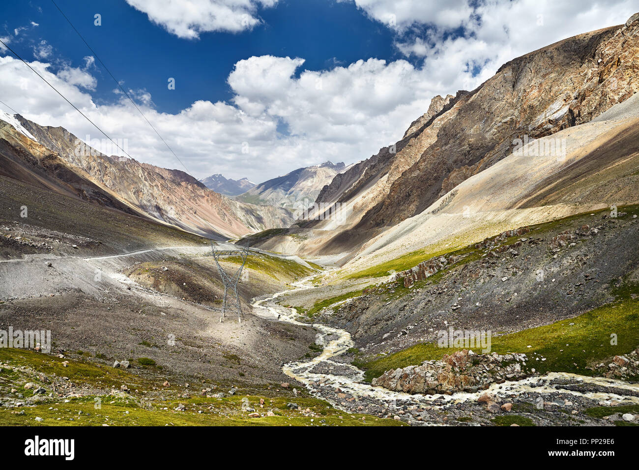Road and white water river in the mountain valley at blue cloudy sky in Kyrgyzstan Stock Photo