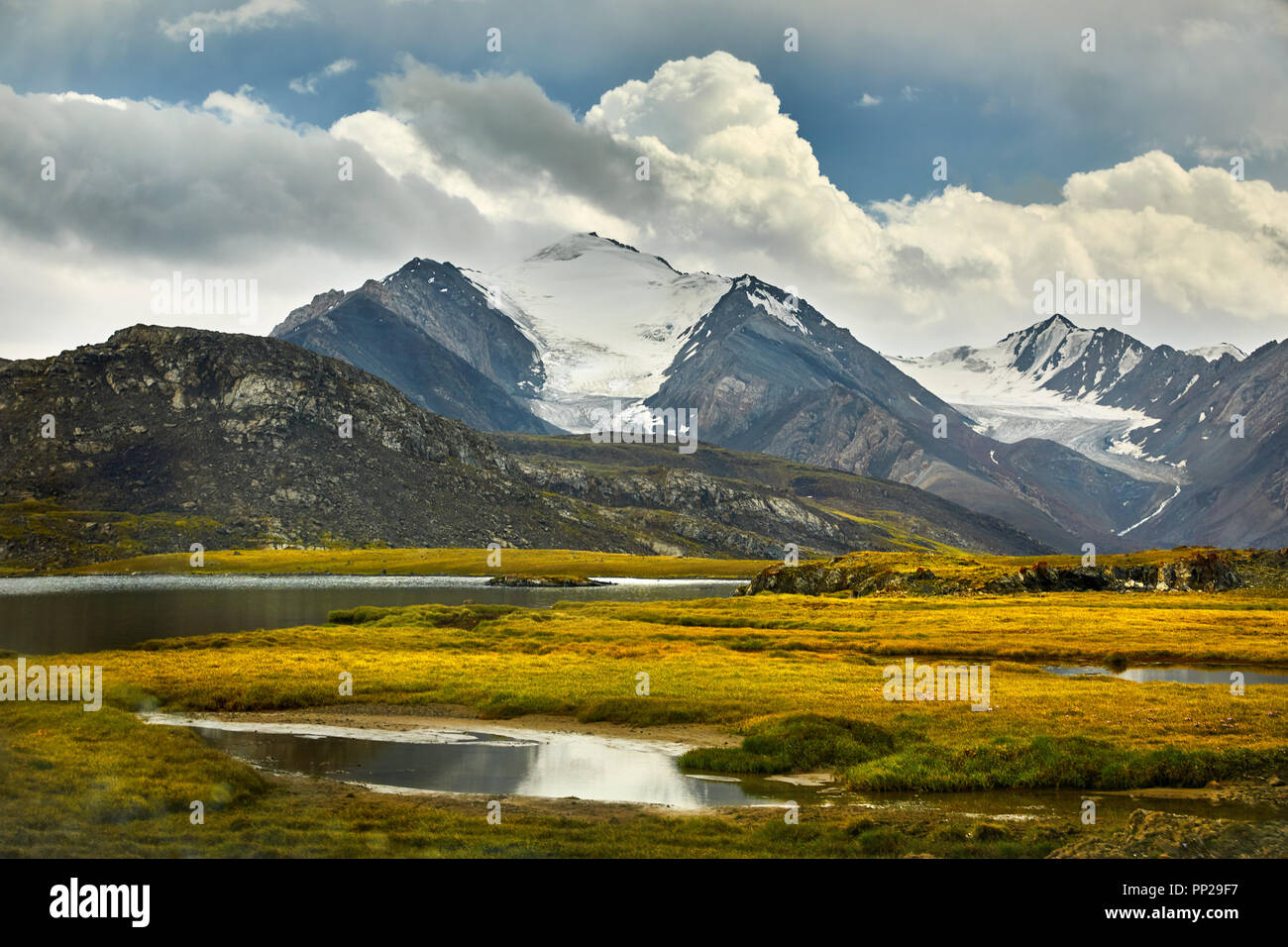 Beautiful Lake and Snowy Mountain in the valley against cloudy sky in Kyrgyzstan Stock Photo