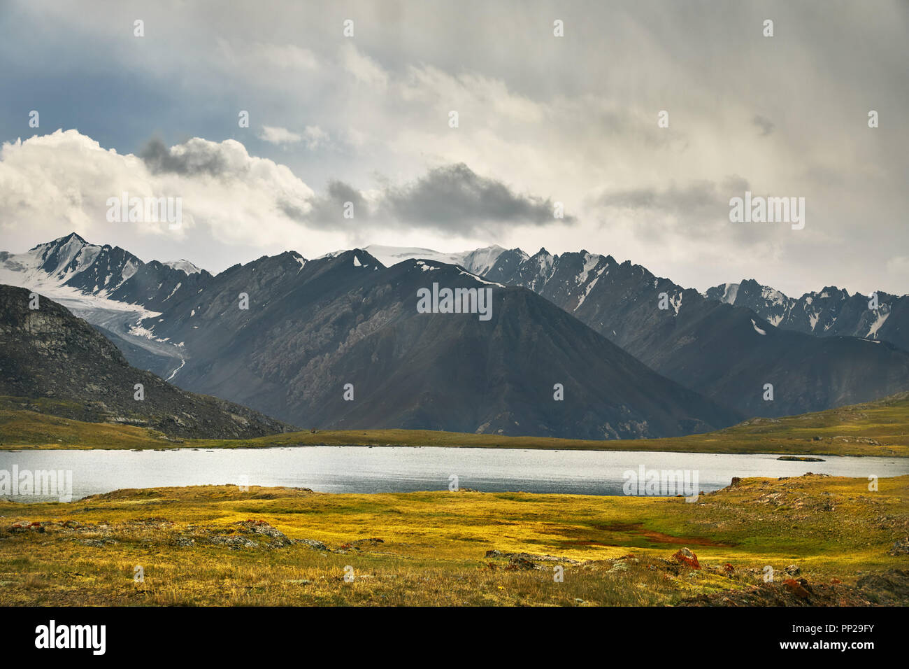 Beautiful Lake and Mountain Range in the valley against cloudy sky in Kyrgyzstan Stock Photo