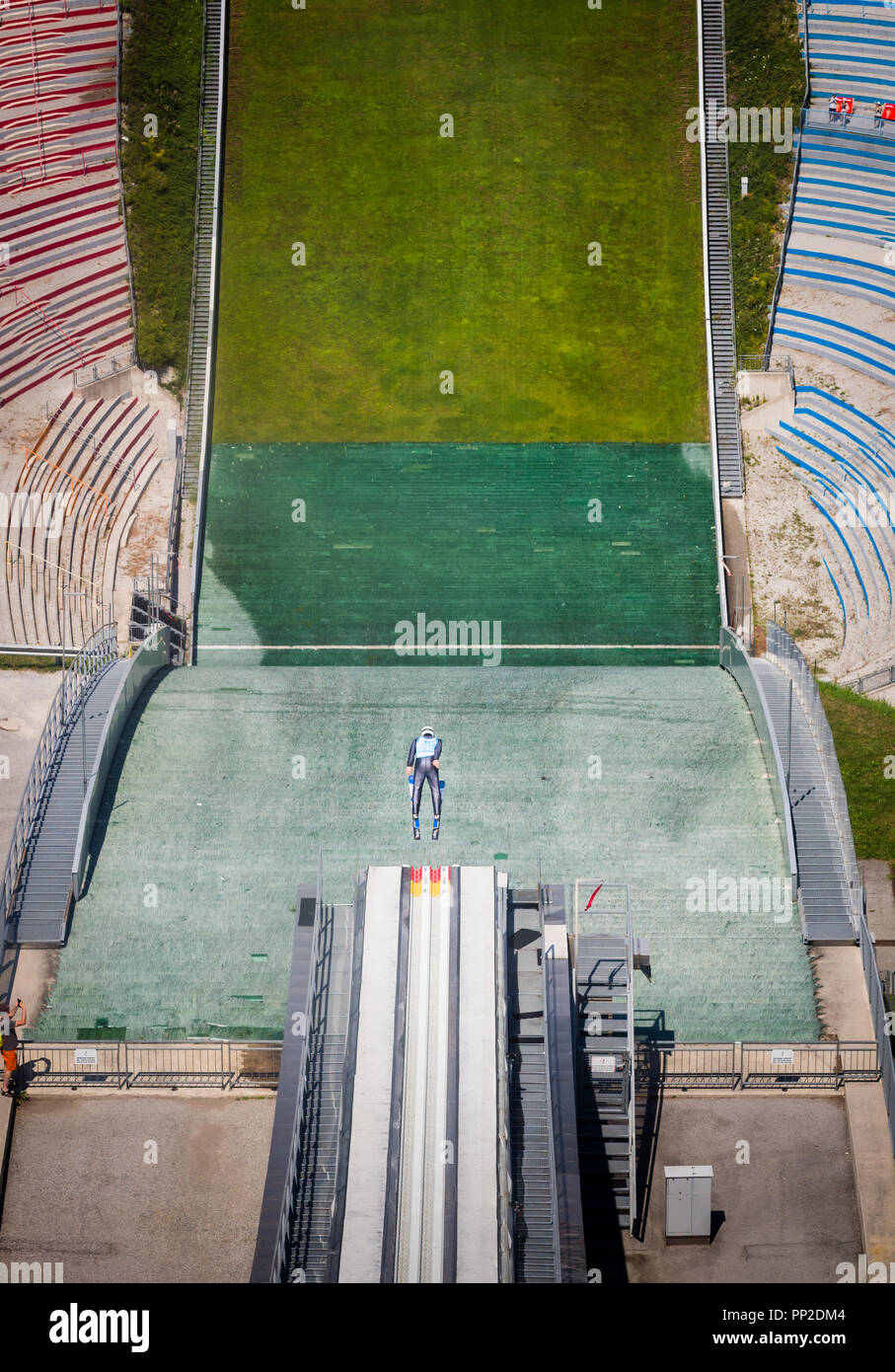 A ski jumper is taking off the Bergisel Ski Jump in Innsbruck (Austria) during a summer training jump on August 1st, 2018. Stock Photo