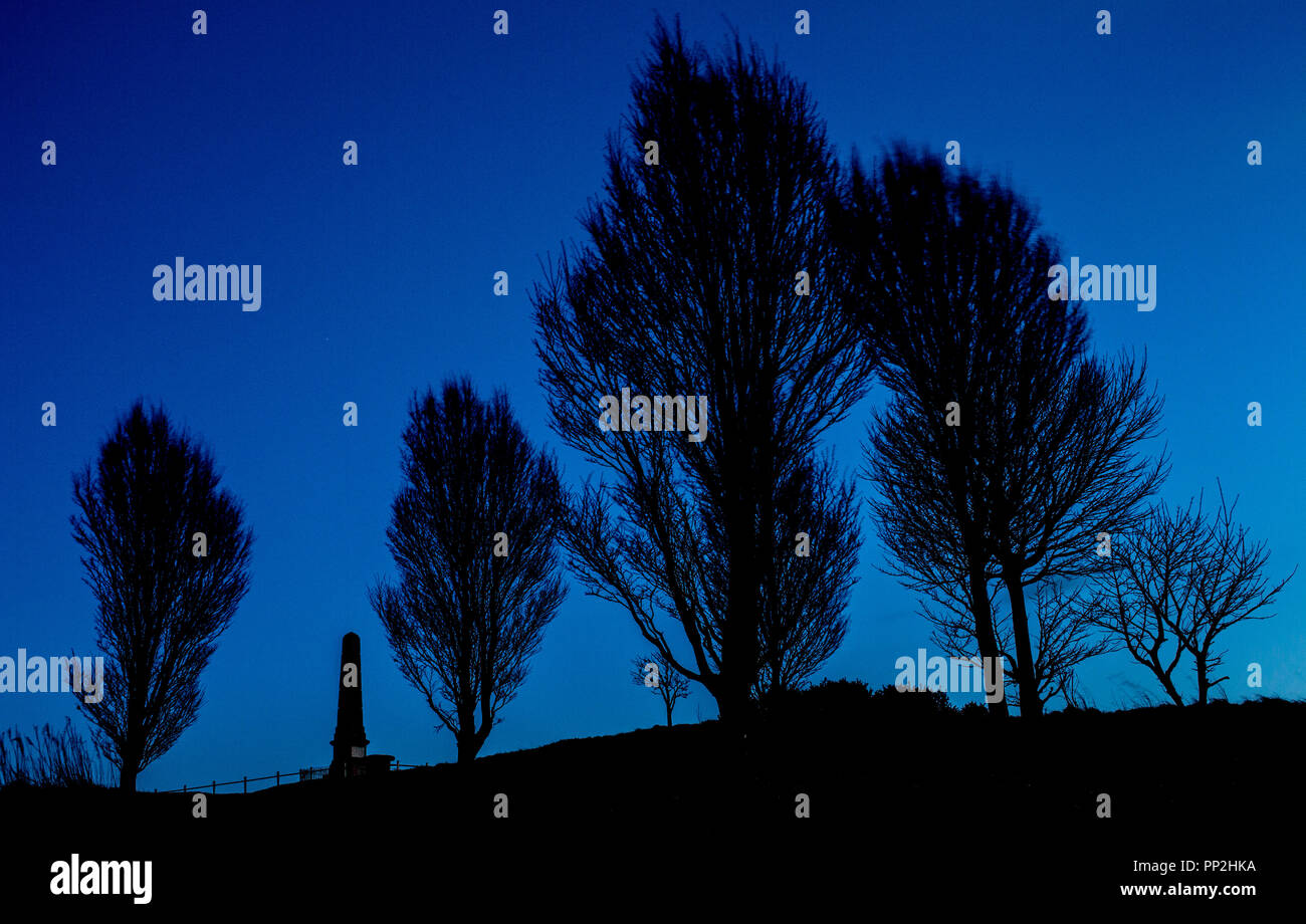 Silhouette trees with cenotaph on hillside, Werneth Low, Stockport, UK Stock Photo