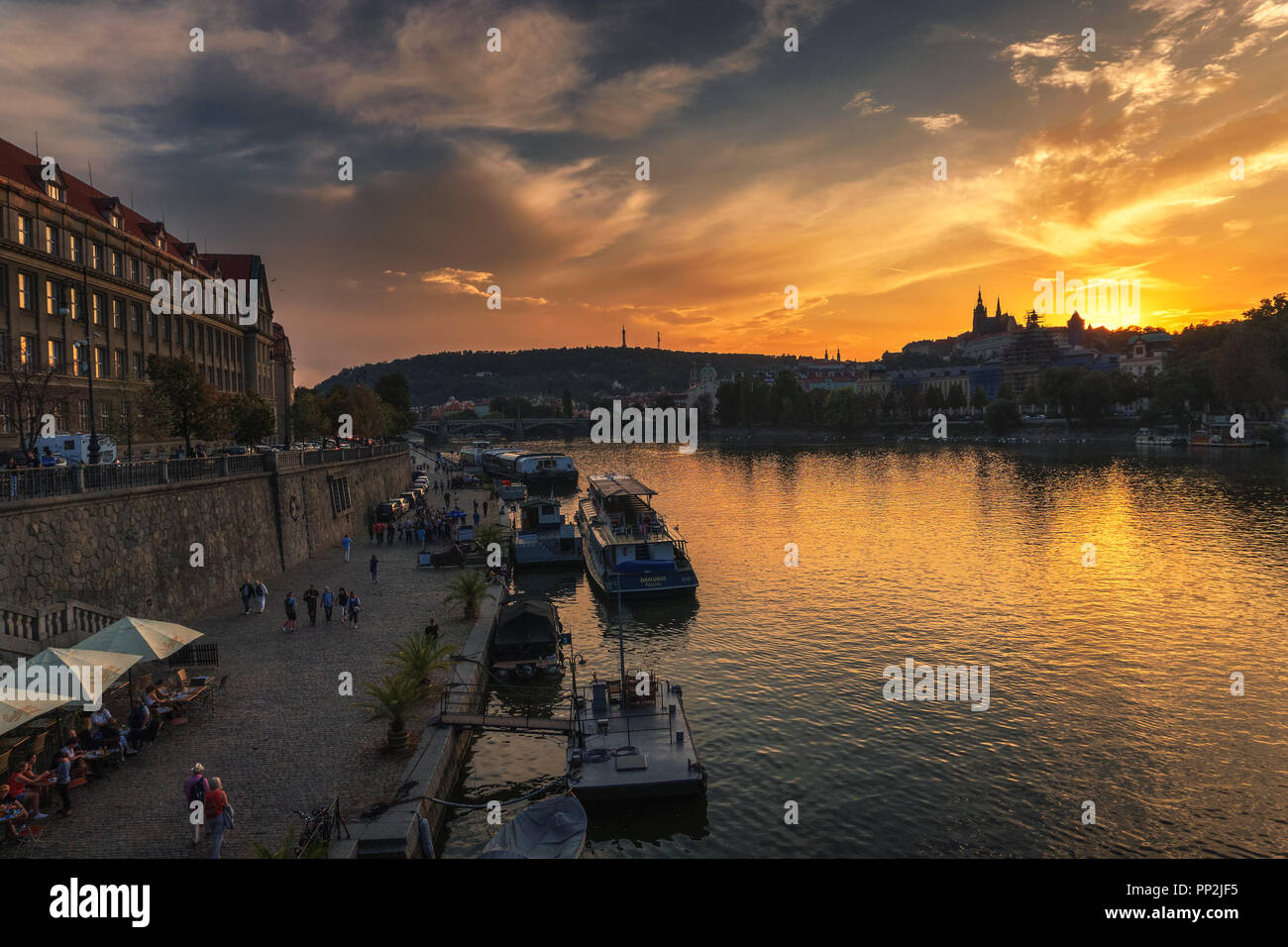 Prague, Czechia - September 19, 2018 : People walk along the Vltava river on the paved river bank known as Naplavka with boats, restaurants and views  Stock Photo