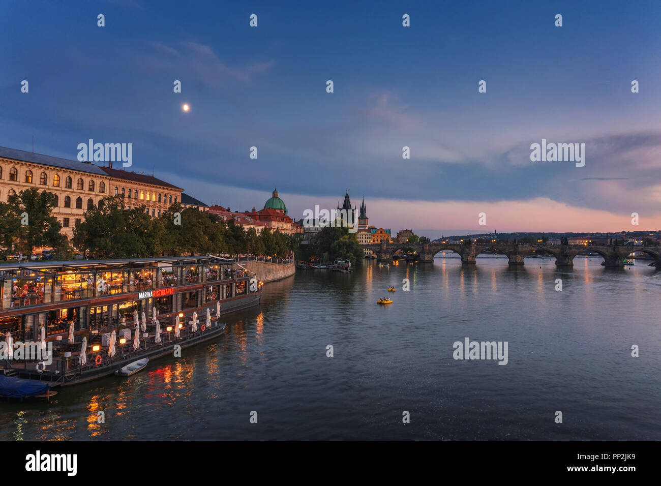 Prague, Czechia - September 19, 2018 : People eat at the famous Marina restaurant along the Vltava river with Charles bridge in the background at suns Stock Photo