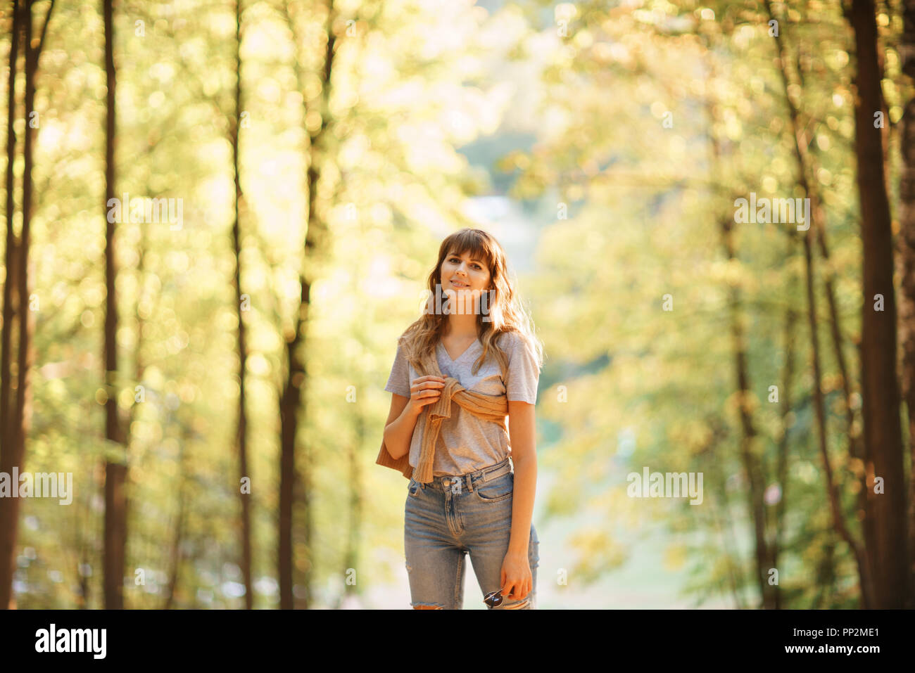 Portrait of young woman in autumn park. Trees with yellow foliage in ...