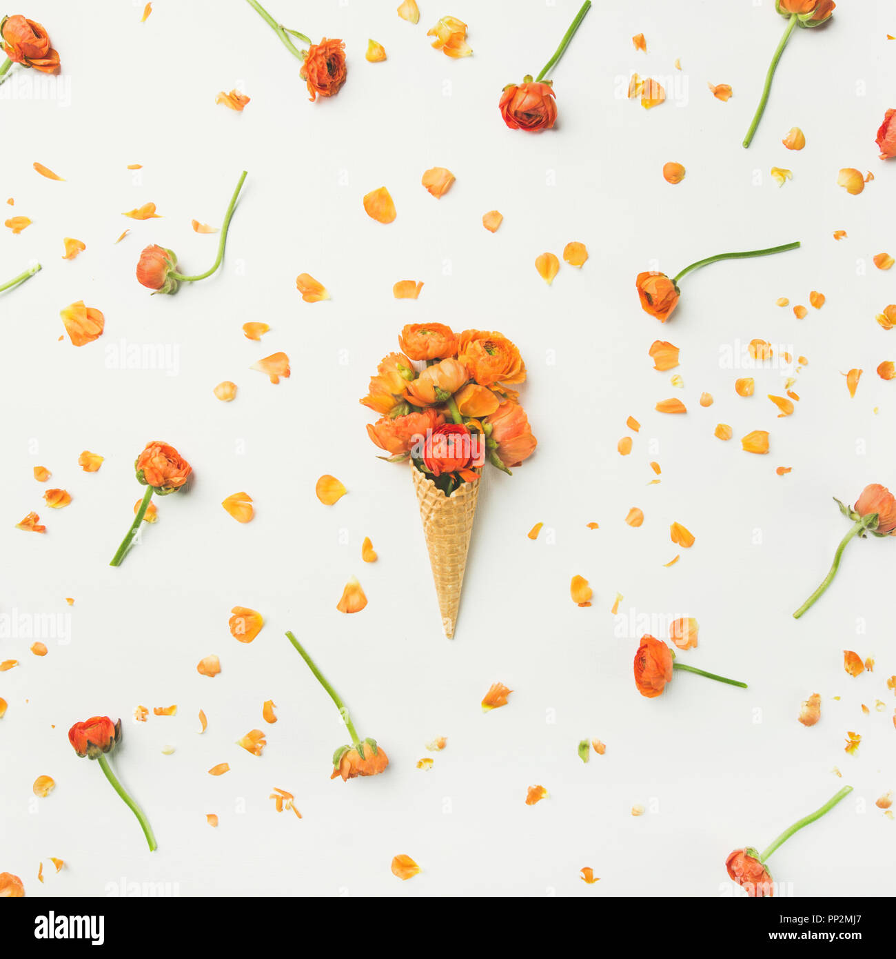 Waffle cone with orange buttercup flowers. Spring or summer mood concept Stock Photo