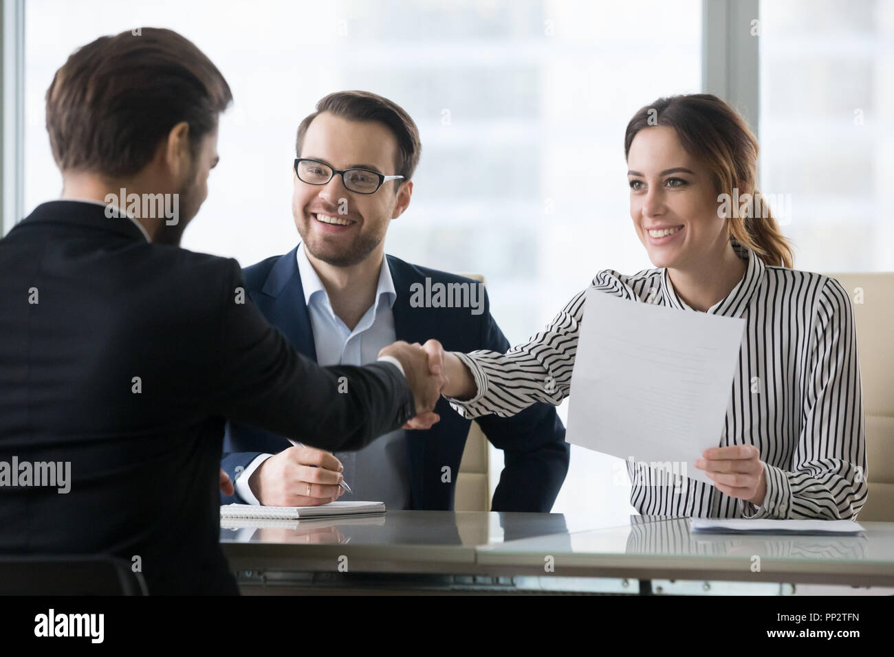 Smiling employers handshaking male candidate congratulating with Stock Photo