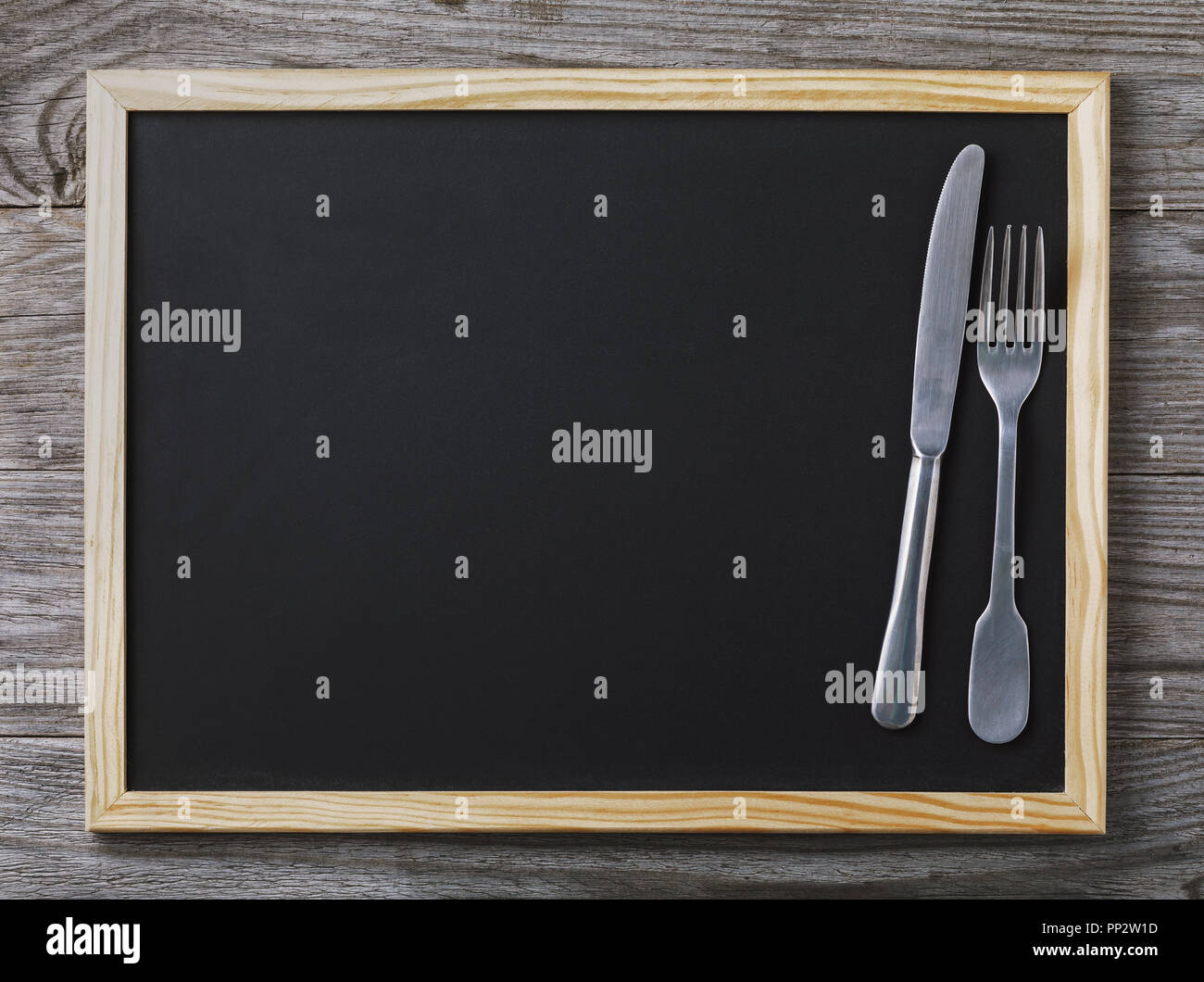 Empty menu blackboard with knife and fork on wooden background with copy space Stock Photo