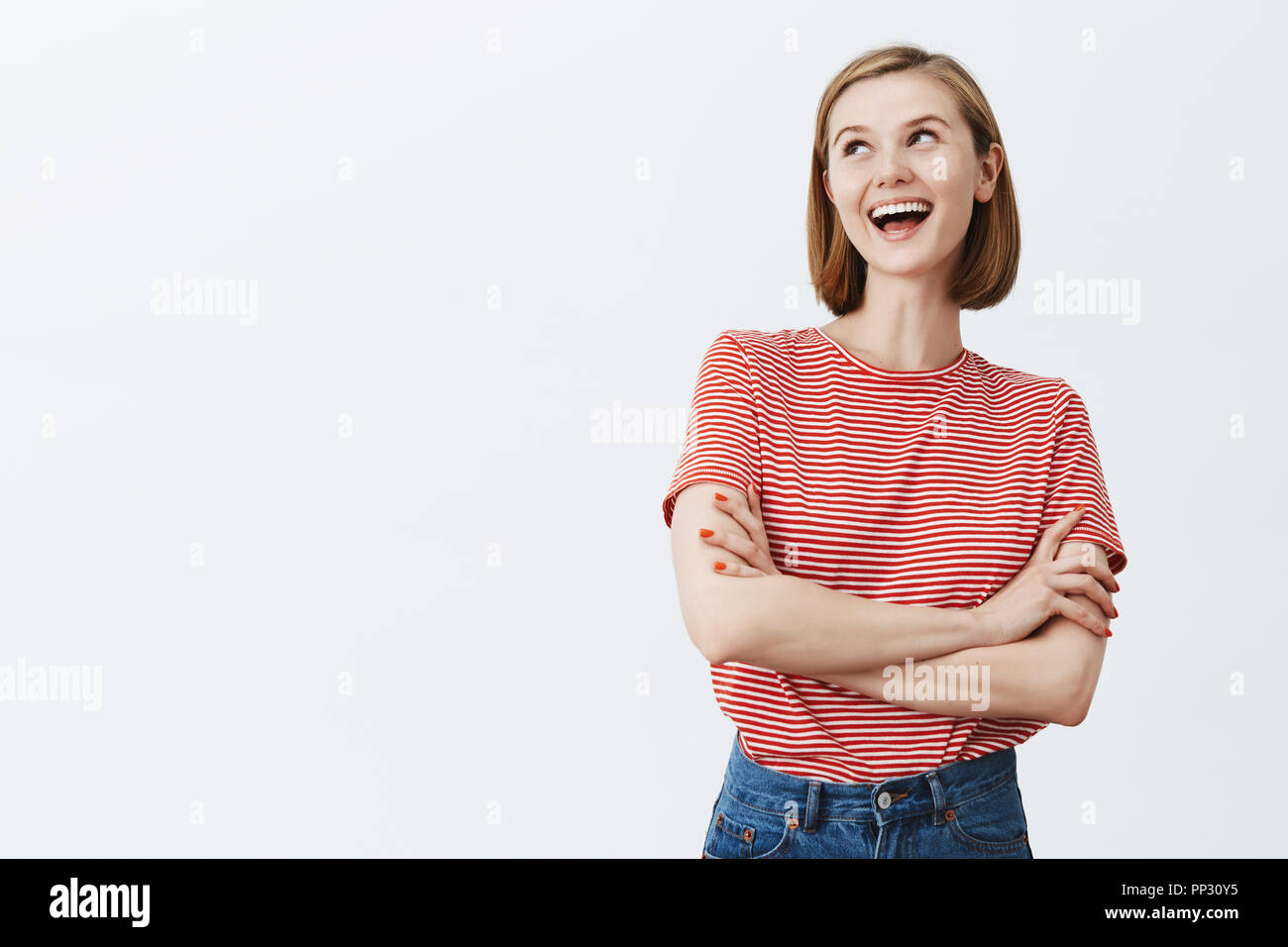 Girl laughing over dumb friend, being arrogant. Joyful triumphing self-assured female with short haircut, holding hands crossed, laughing with contempt, being top of class, showing snobbish character Stock Photo