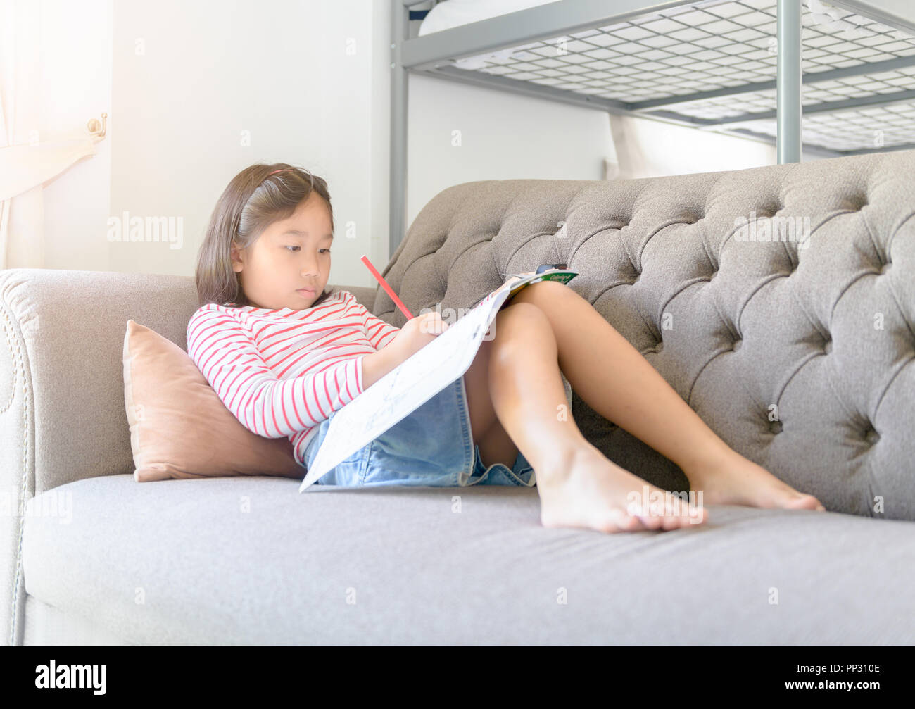 cute girl drawing on sofa in bedroom, education concept Stock Photo