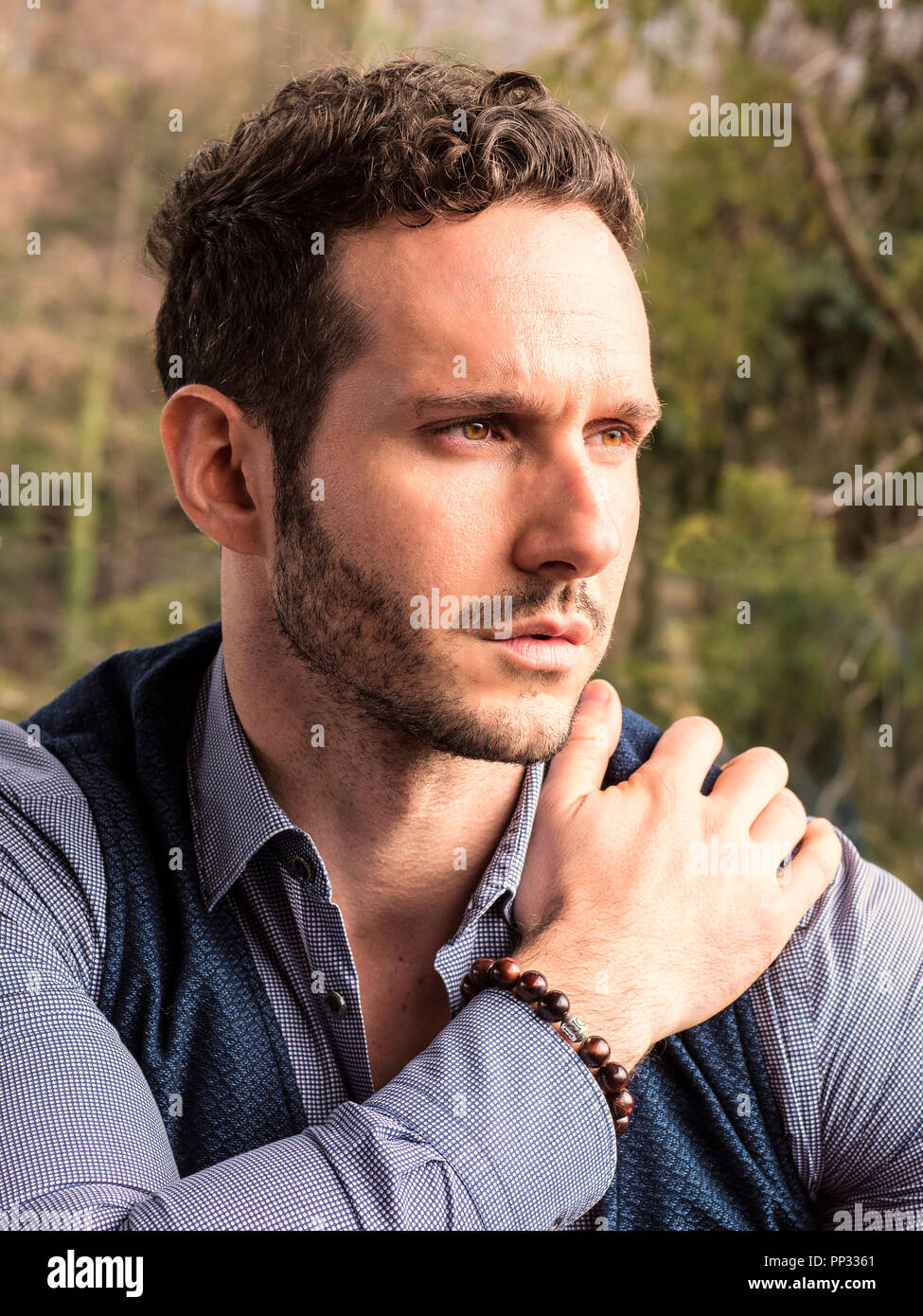 Handsome elegant man outdoor, wearing shirt and vest, looking away to a ...