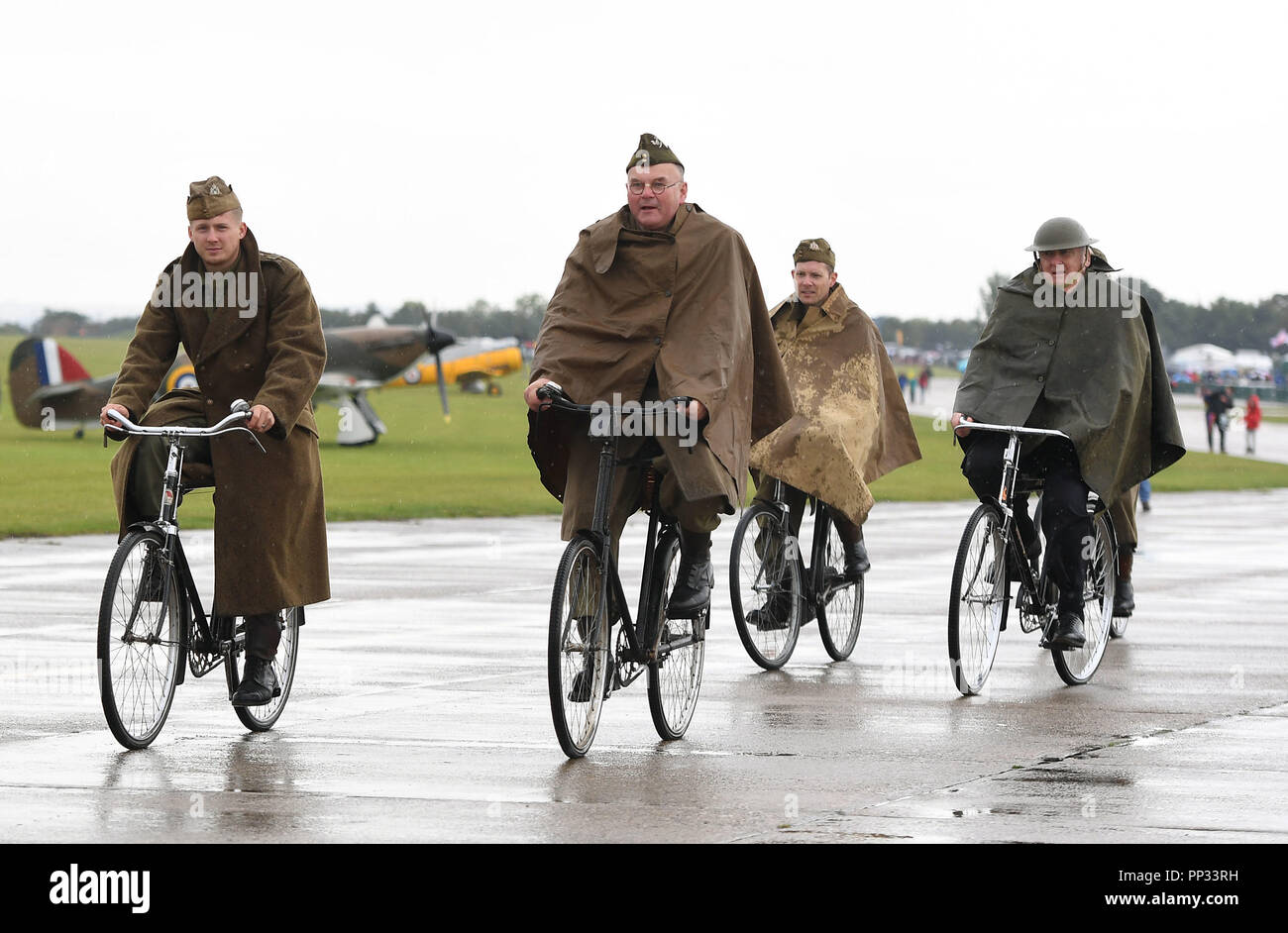 Historical reenactment members cycle along the taxiway during the Battle of Britain Air Show at the Imperial War Museum in Duxford, Cambridgeshire. Stock Photo
