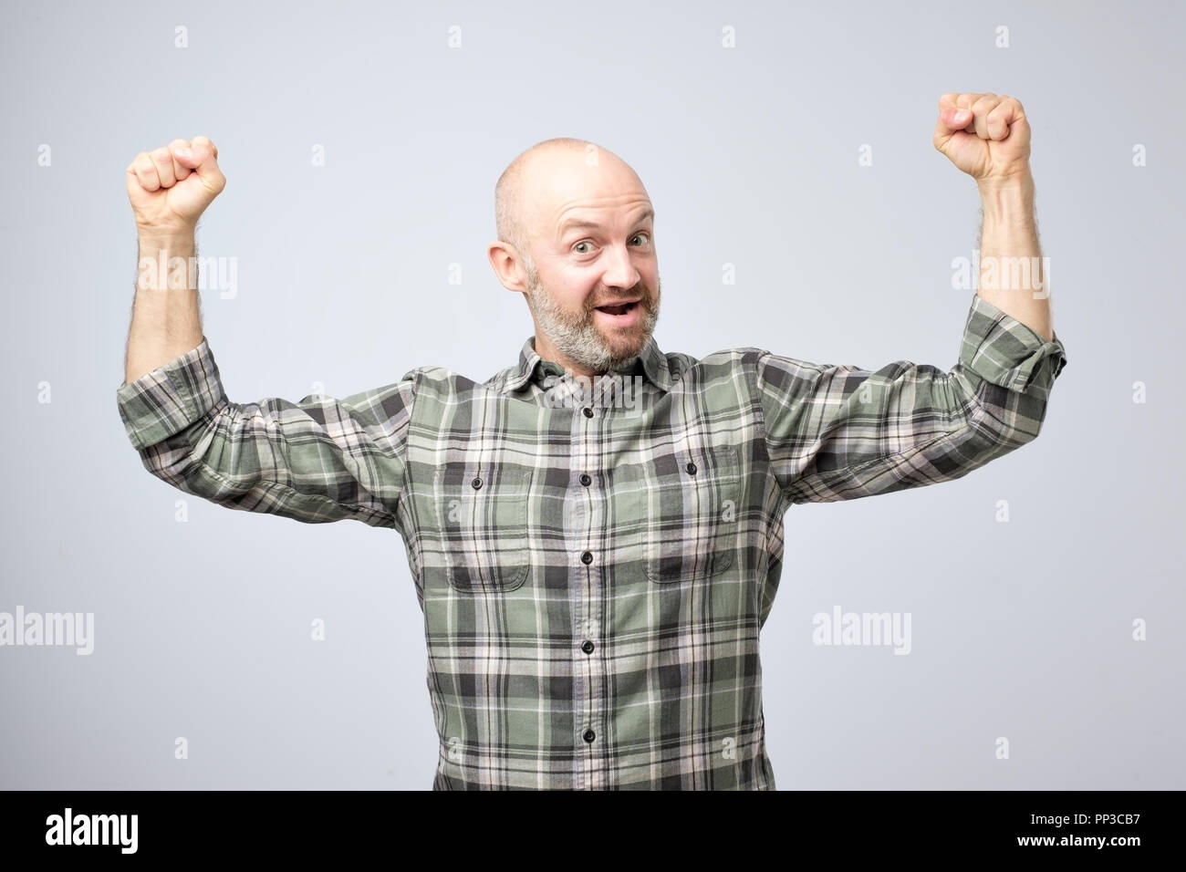 Positive emotional man smiles, shows muscles on his arms, feels proud to be strong. Stock Photo
