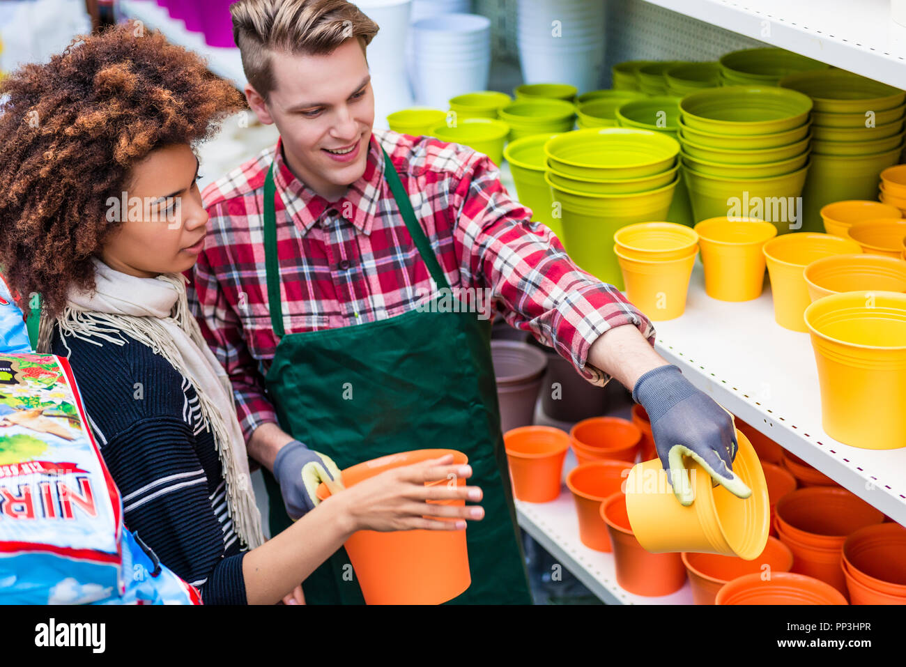 Customer buying plastic pots at the advice of a helpful worker Stock Photo