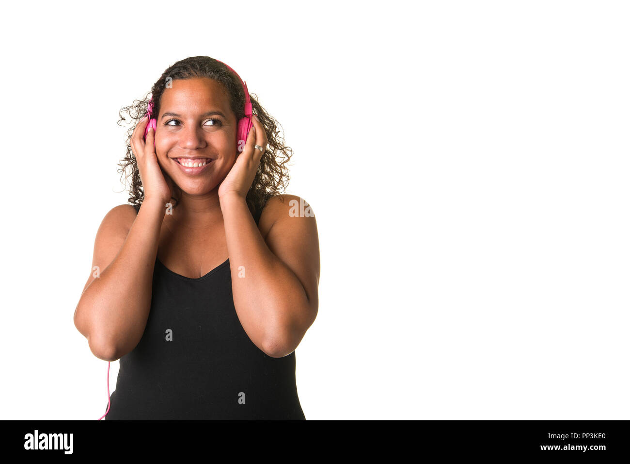 Young pretty black woman listening to music on a pink headphone isolated on a white background Stock Photo