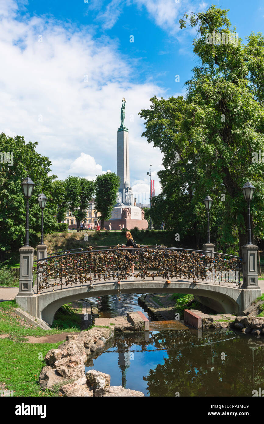 Riga park, view on a summer afternoon of an ornamental bridge in Bastion Hill Park and of the Freedom Monument in the City Canal area of Riga, Latvia. Stock Photo