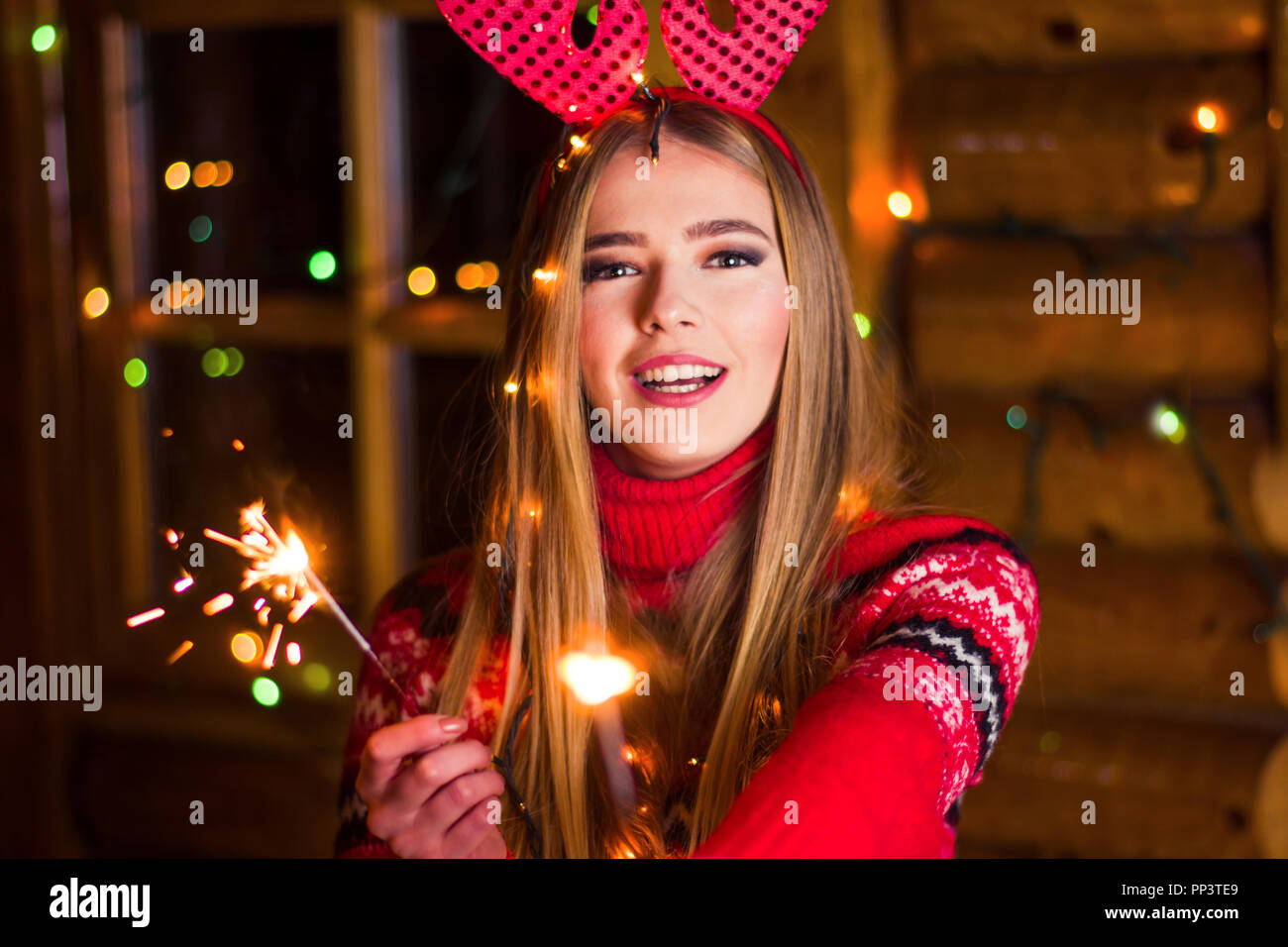 Beautiful girl with Christmas sparkles in a wooden log cabin Stock Photo